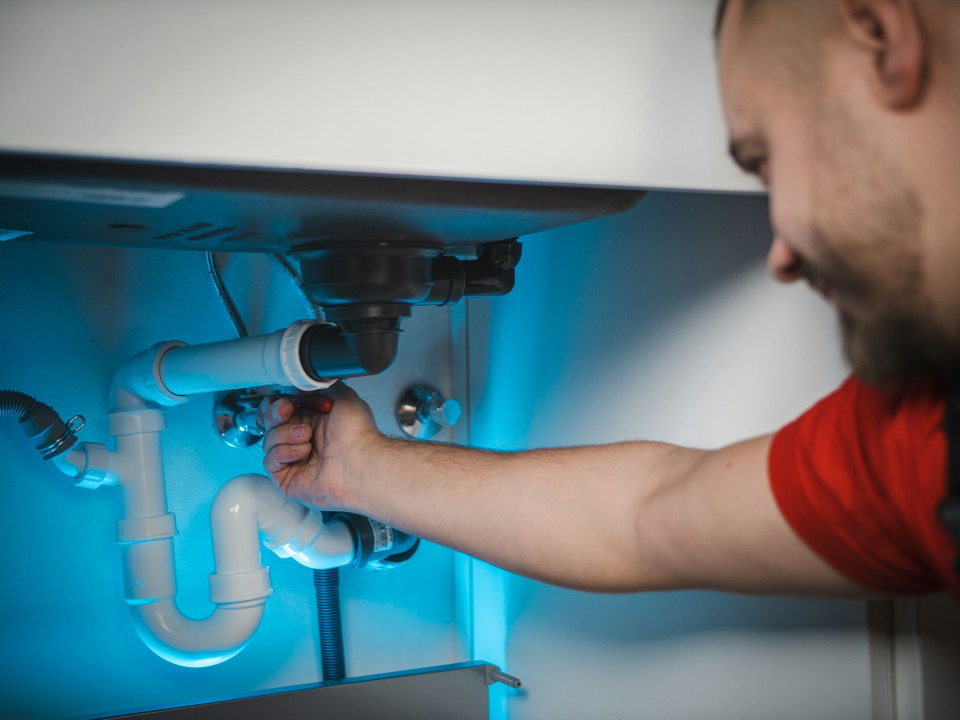Installateur arbeitet an einem Siphon unter einem Waschbecken