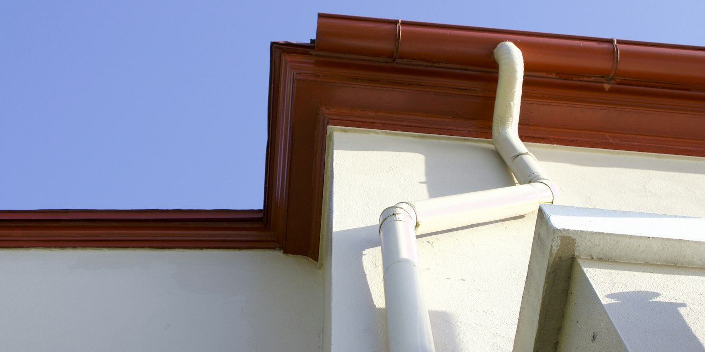 Dachrinne mit Rinnenkessel und angeschlossenem Fallrohr an einer Hausecke