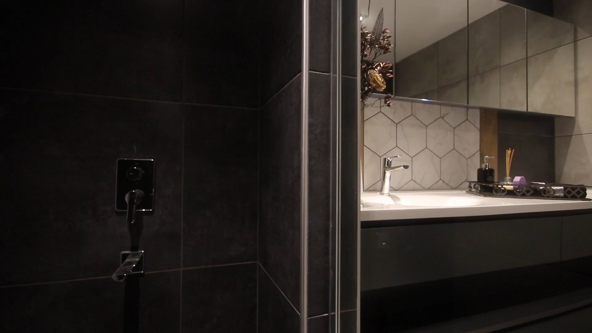 Modernes Badezimmer mit dunklen Fliesen, Unterputzarmatur und Waschtisch vor Wabenfliesen
