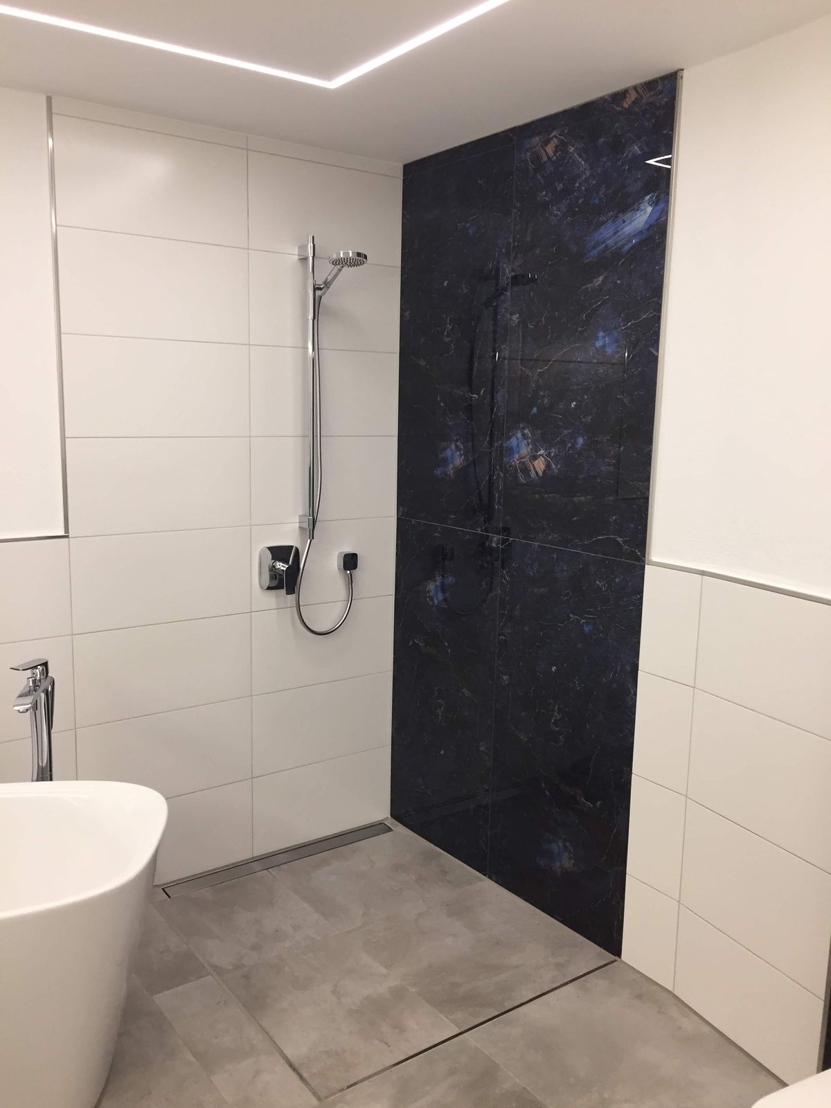 Bodengleiche Dusche mit Linienentwässerung und dunkler Glasfliesenfläche