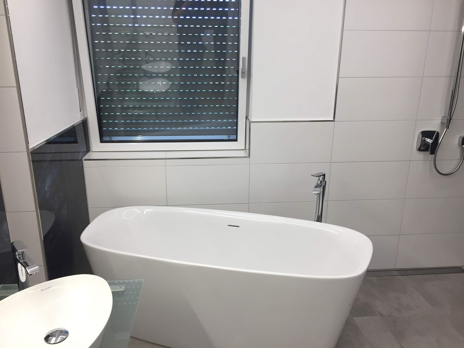Freistehende Badewanne vor einem Fenster im fertigen Badezimmer
