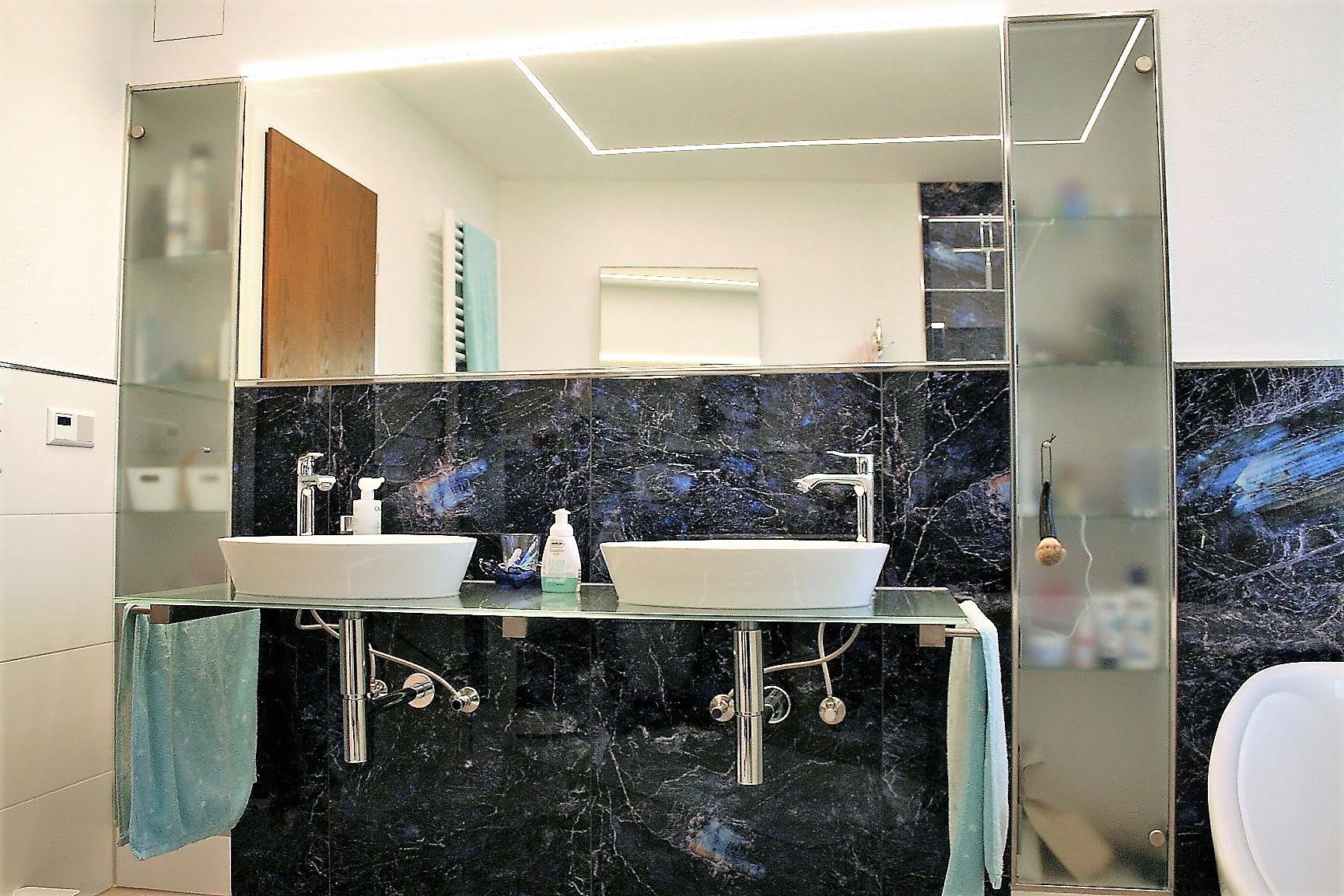 Waschtischbereich mit großer Spiegelfläche und seitlichen Glasschränken