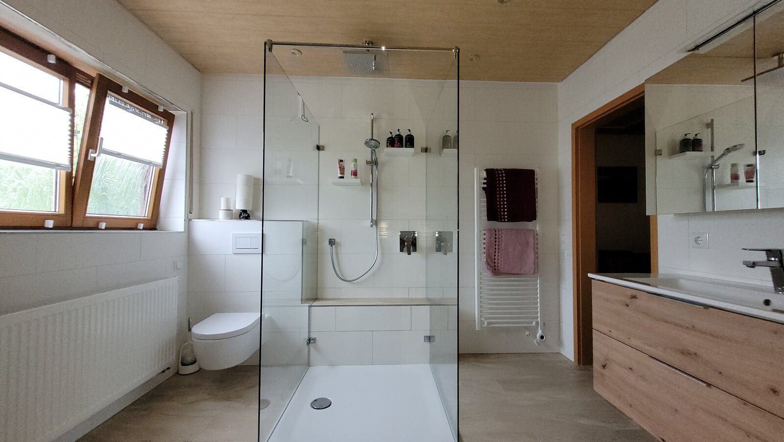 Dachgeschossbad mit freistehender Dusche, Wand-WC und Waschtisch mit Holzfront