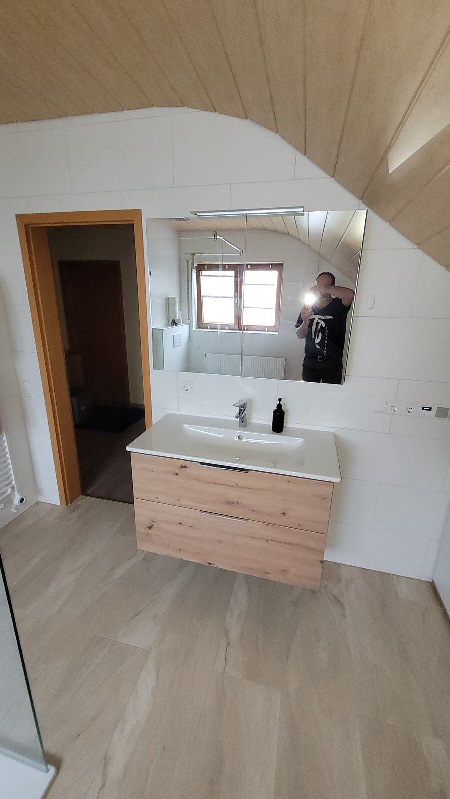 Wandhängender Waschtisch mit Holzfront und großflächigem Spiegel unter der Dachschräge