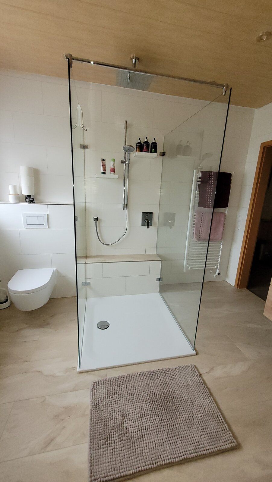 Freistehende Dusche mit Glasabtrennung und gemauerter Sitzbank in einem Dachgeschossbad