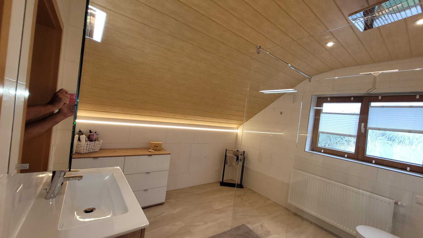 Umlaufendes LED-Lichtband entlang der holzverkleideten Dachschräge über dem Sideboard