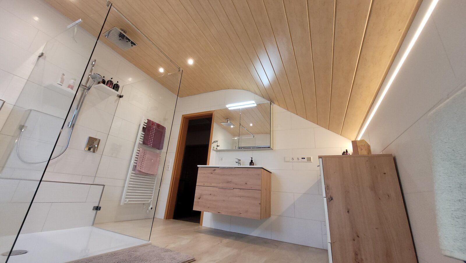 Dachgeschossbad in Oberstenfeld mit Glasdusche, Holzdecke und LED-Lichtband