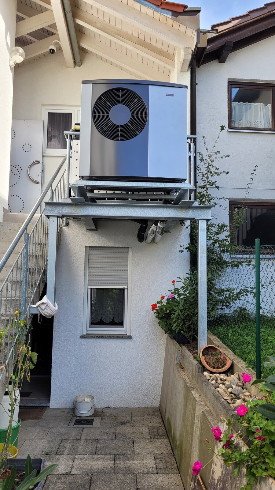 NIBE-Wärmepumpe auf einem verzinkten Stahlpodest an einem Wohnhaus