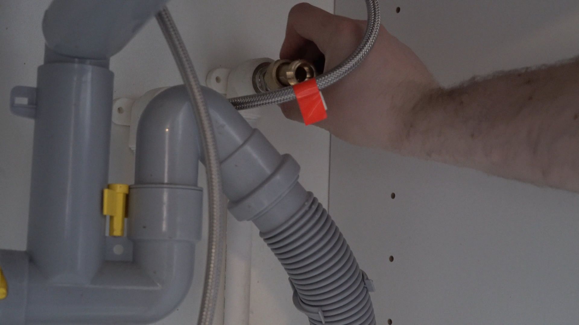 Installateur montiert von Hand die Wasseranschlüsse unter einem Waschbecken