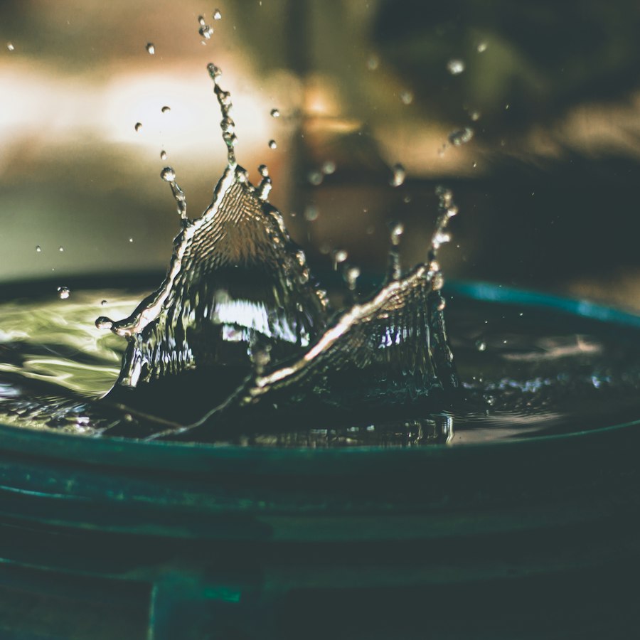 Wassertropfen fällt in ein mit Wasser gefülltes Gefäß