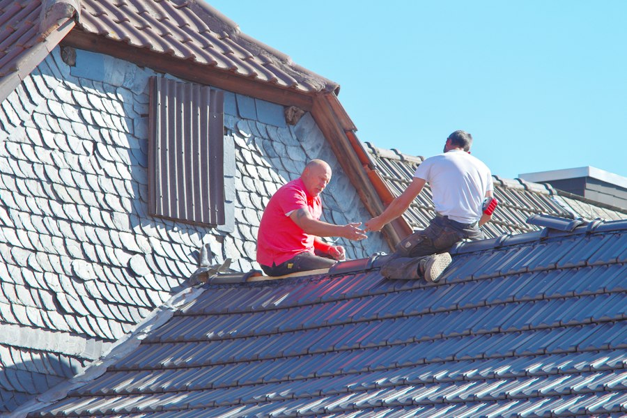 Zwei Handwerker bei Klempner- und Flaschnerarbeiten am Dach